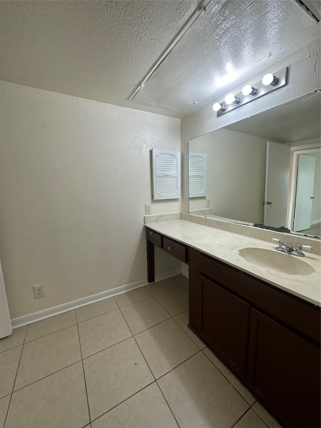 bathroom with a textured ceiling, baseboards, tile patterned flooring, and vanity