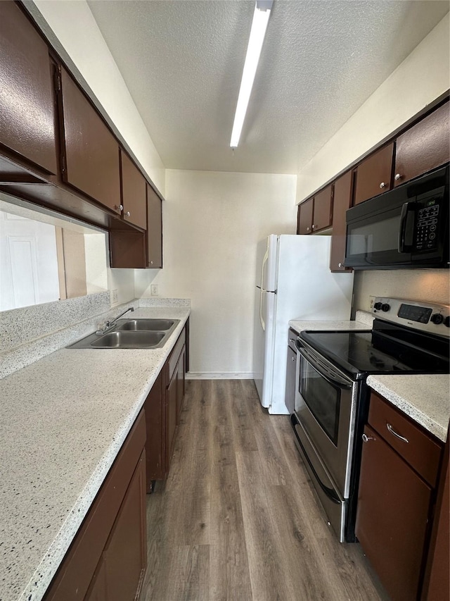 kitchen with electric range, black microwave, a sink, light countertops, and dark wood-style floors