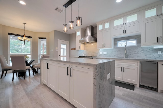 kitchen with wall chimney exhaust hood, a kitchen island, light wood-style flooring, healthy amount of natural light, and recessed lighting