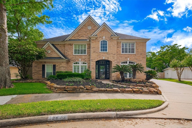 view of front of house featuring brick siding, concrete driveway, and an outbuilding