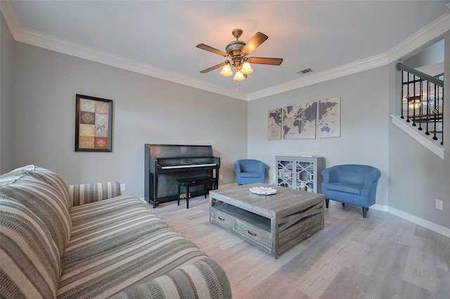 living area featuring stairway, crown molding, light wood-style floors, ceiling fan, and baseboards