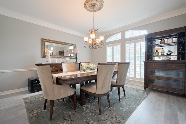 dining room with a chandelier, ornamental molding, wood finished floors, and baseboards