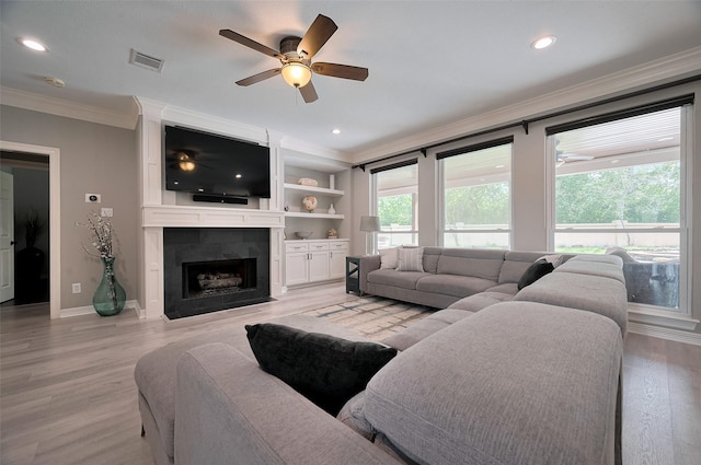living area with crown molding, ceiling fan, light wood-style flooring, a fireplace, and baseboards