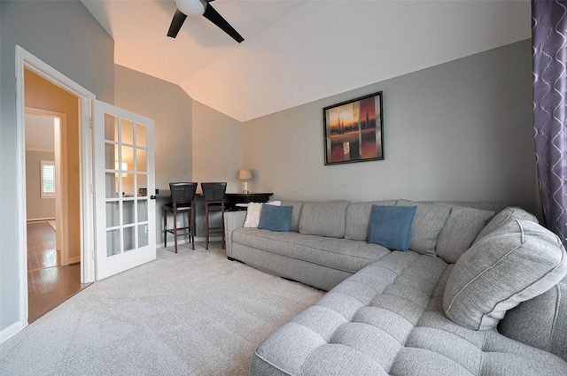 carpeted living room with ceiling fan, vaulted ceiling, and baseboards