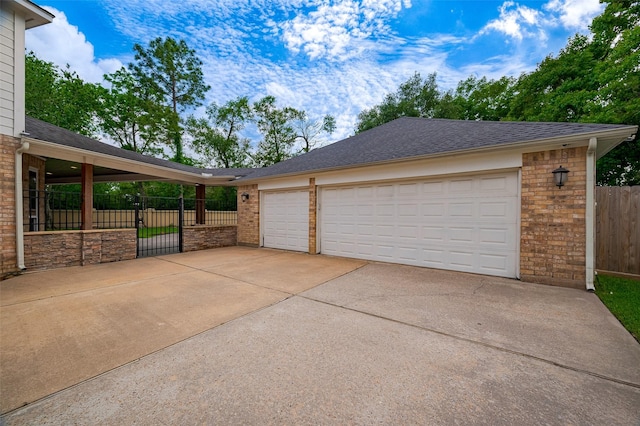 garage with driveway, fence, and a gate