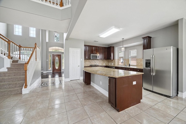 kitchen featuring a kitchen island, appliances with stainless steel finishes, tasteful backsplash, dark brown cabinets, and a sink