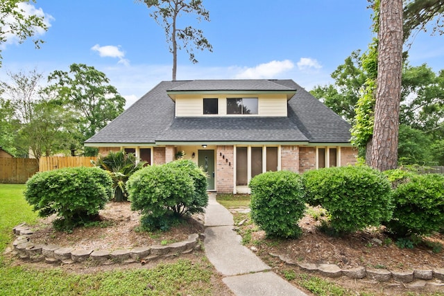 bungalow with brick siding, roof with shingles, and fence