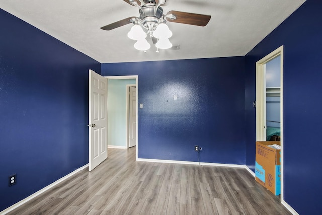 unfurnished bedroom featuring baseboards, a ceiling fan, wood finished floors, and visible vents