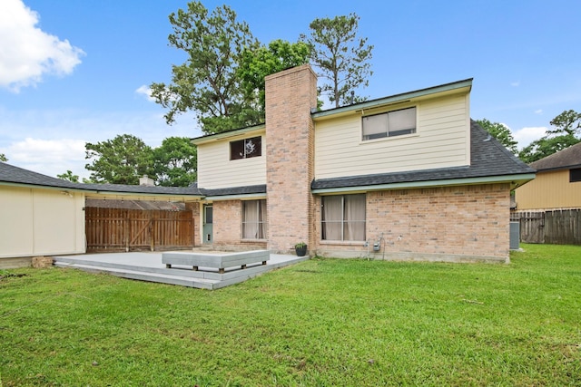 rear view of property featuring fence, brick siding, a wooden deck, a chimney, and a yard