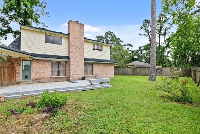 back of property with brick siding, a wooden deck, a fenced backyard, and a chimney