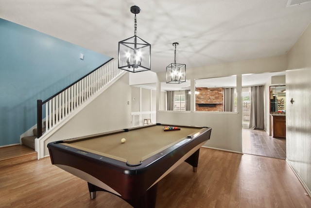game room featuring an inviting chandelier, wood finished floors, and pool table