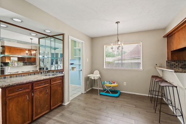 interior space featuring a sink, light wood finished floors, a chandelier, and decorative light fixtures