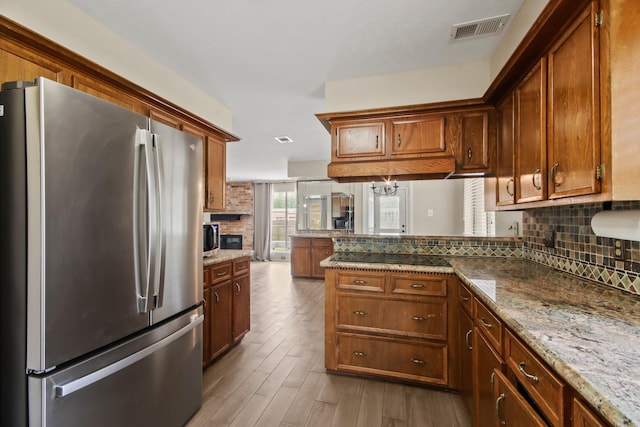 kitchen with decorative backsplash, stainless steel appliances, a peninsula, and visible vents