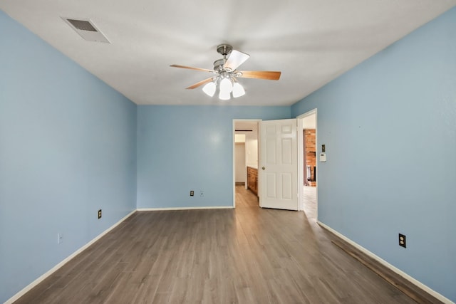 spare room featuring ceiling fan, visible vents, baseboards, and wood finished floors