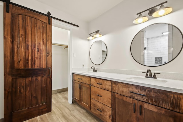 full bathroom with a sink, double vanity, and wood finished floors
