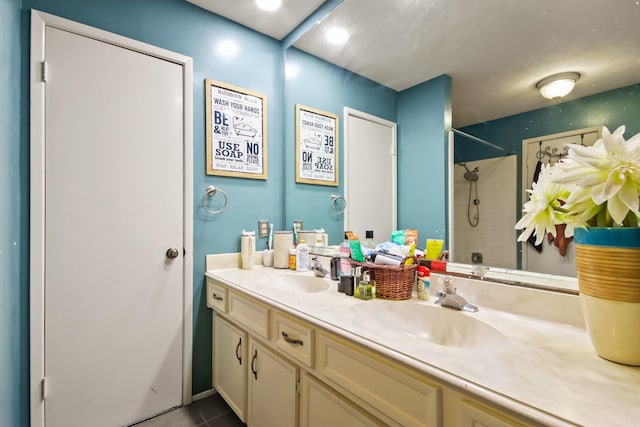 full bathroom with a sink, tile patterned flooring, a tile shower, and double vanity