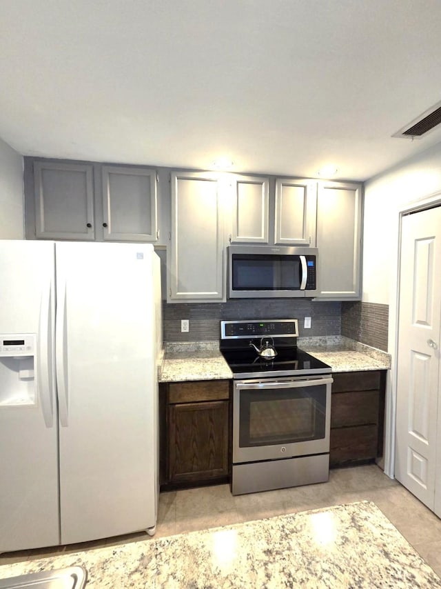 11711 Memorial Dr Unit 97, Houston, TX 77024 - kitchen featuring visible vents, appliances with stainless steel finishes, light stone countertops, and tasteful backsplash