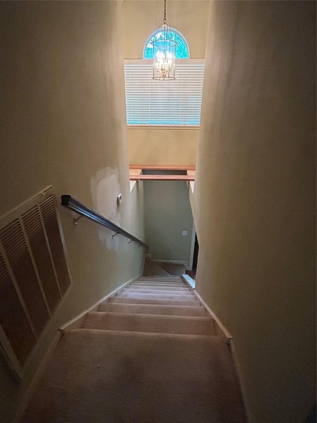 staircase with an inviting chandelier, carpet, and visible vents