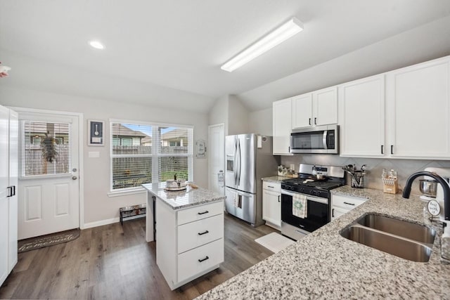 kitchen with lofted ceiling, a kitchen island, a sink, dark wood finished floors, and appliances with stainless steel finishes