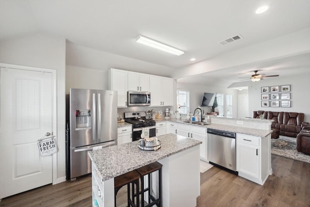 kitchen with a sink, stainless steel appliances, open floor plan, a peninsula, and visible vents