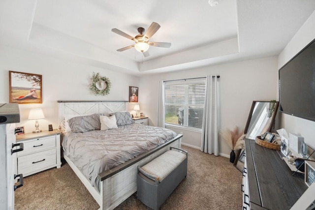 carpeted bedroom featuring baseboards, ceiling fan, and a tray ceiling