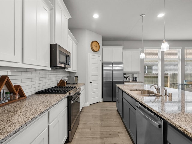 kitchen featuring a sink, decorative backsplash, appliances with stainless steel finishes, and white cabinets