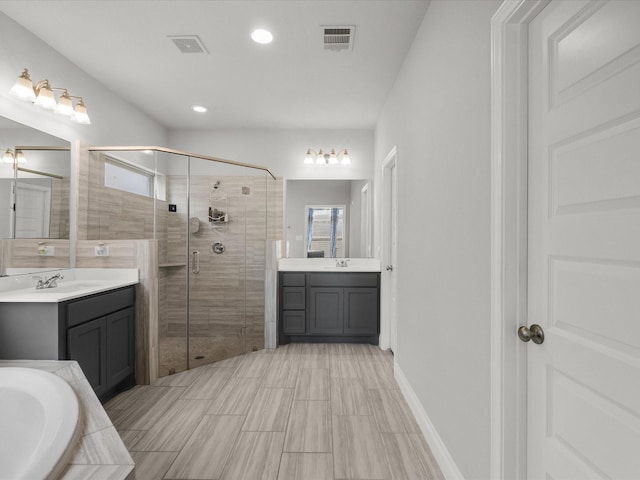 full bathroom with visible vents, a bath, two vanities, a sink, and a stall shower