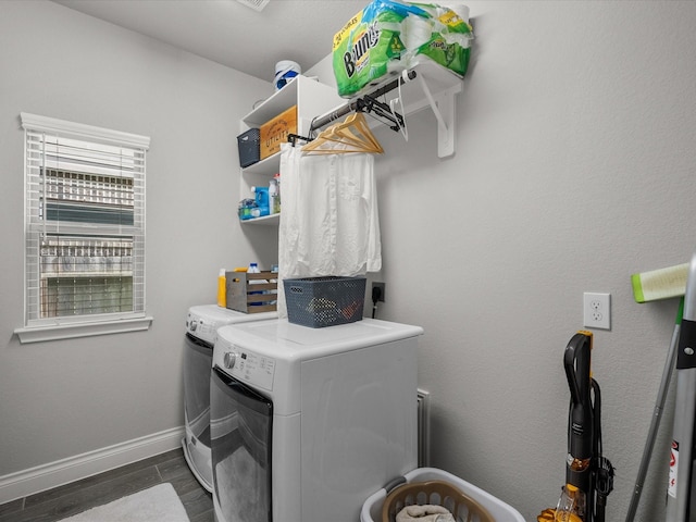 clothes washing area with separate washer and dryer, laundry area, dark wood finished floors, and baseboards