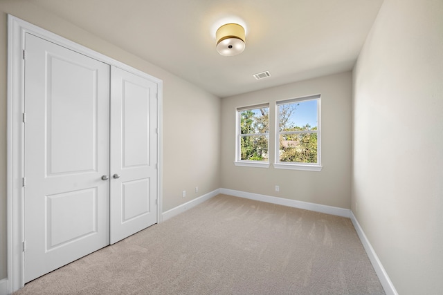 unfurnished bedroom with carpet floors, baseboards, visible vents, and a closet