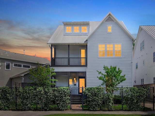 view of front of home with a fenced front yard, metal roof, and a balcony