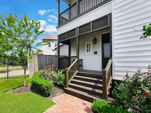 entrance to property with fence and a balcony