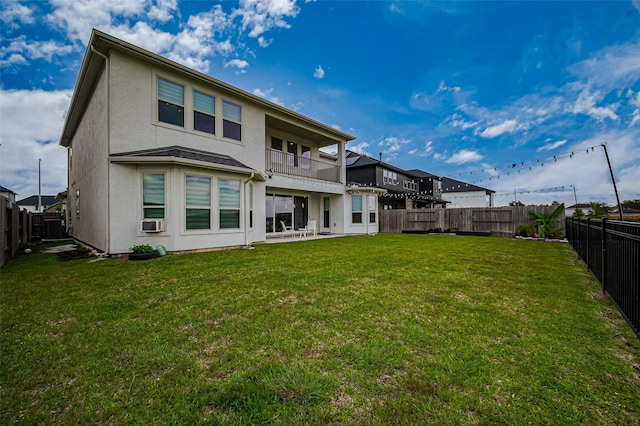 rear view of house with a lawn, a balcony, a fenced backyard, and stucco siding