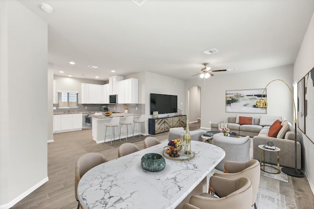 dining room featuring visible vents, arched walkways, light wood-type flooring, baseboards, and recessed lighting