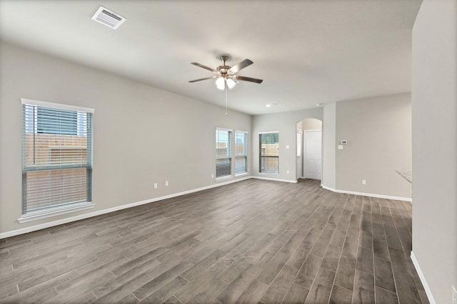 spare room featuring baseboards, a ceiling fan, and dark wood-style floors