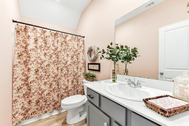bathroom featuring visible vents, vanity, wood finished floors, toilet, and vaulted ceiling