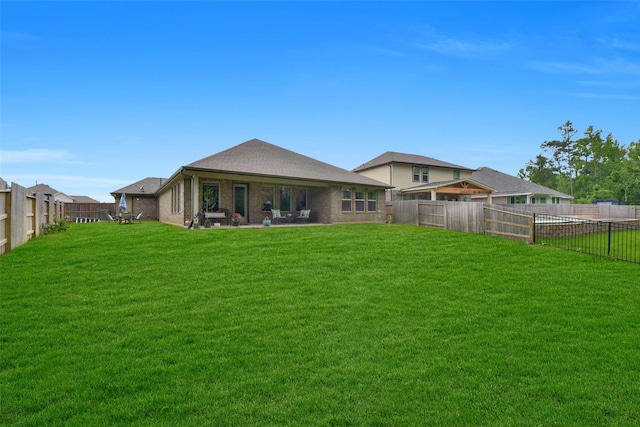 rear view of house featuring brick siding, a fenced backyard, and a yard