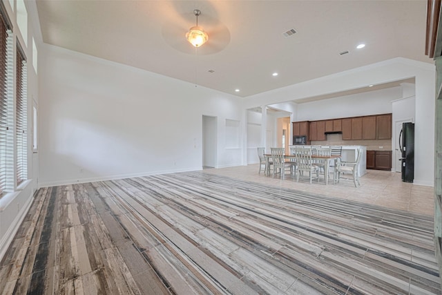 unfurnished living room with baseboards, a ceiling fan, light wood-style flooring, and visible vents