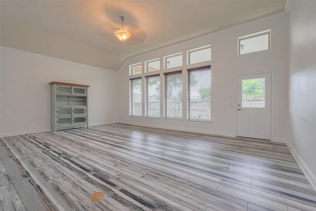 unfurnished living room featuring a ceiling fan, baseboards, vaulted ceiling, and wood finished floors