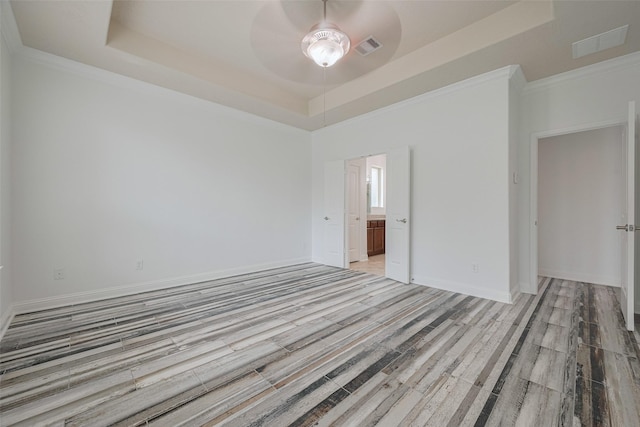 unfurnished room featuring ceiling fan, visible vents, light wood-style flooring, and a raised ceiling