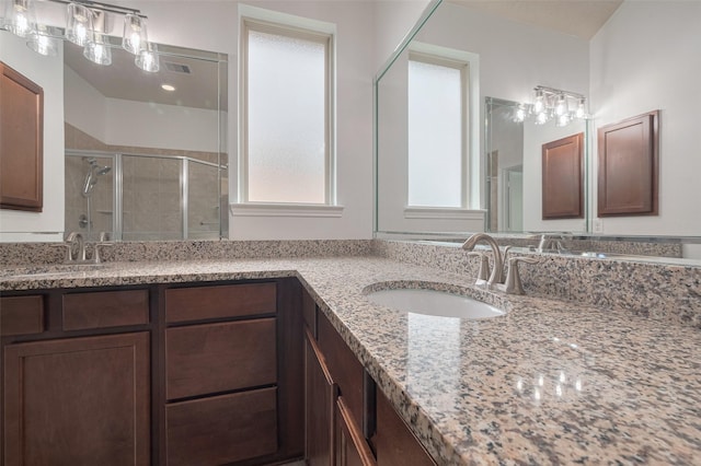 full bathroom with double vanity, a sink, a stall shower, and visible vents