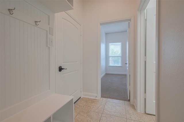 mudroom with baseboards, light colored carpet, and light tile patterned floors