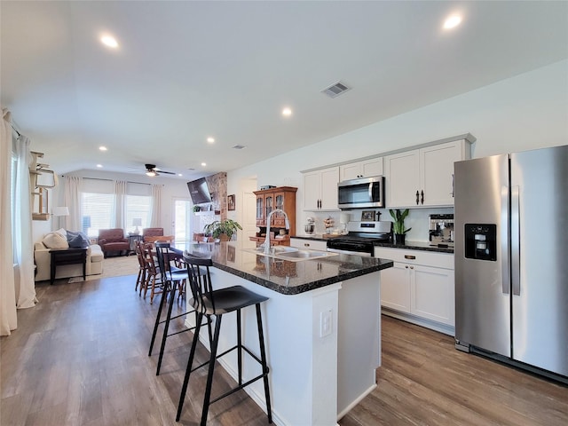 kitchen featuring appliances with stainless steel finishes, a sink, a kitchen breakfast bar, open floor plan, and visible vents