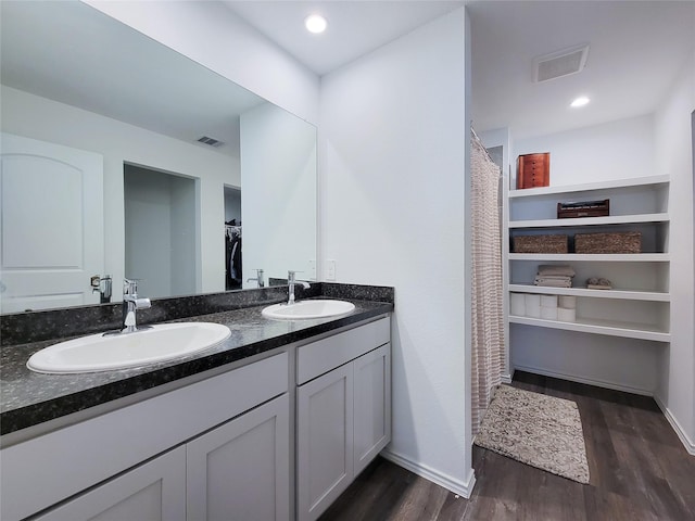 full bathroom with visible vents, a sink, and wood finished floors