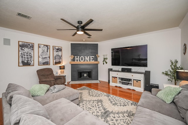 living room featuring ceiling fan, ornamental molding, wood finished floors, and visible vents