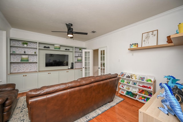 living area with a ceiling fan, french doors, visible vents, crown molding, and light wood finished floors