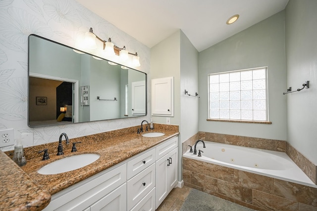 bathroom with double vanity, a whirlpool tub, vaulted ceiling, and a sink
