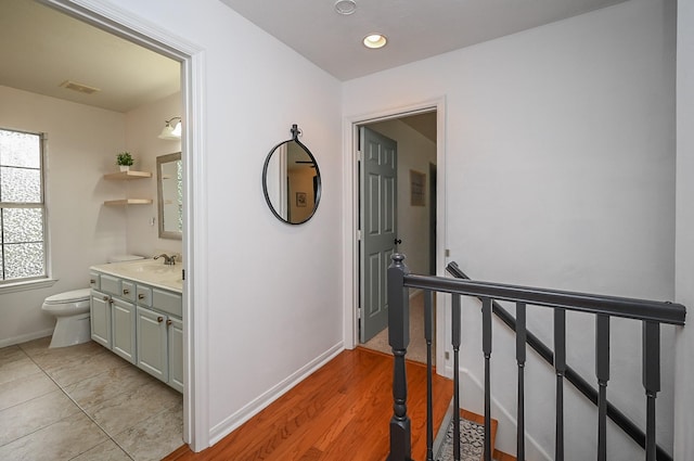 hall featuring a sink, recessed lighting, baseboards, an upstairs landing, and visible vents