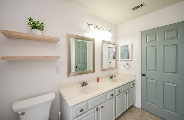 bathroom featuring visible vents, a sink, double vanity, and toilet