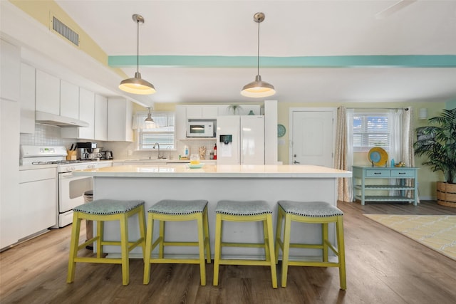22118 Matagorda Dr, Galveston, TX 77554 - kitchen featuring a kitchen breakfast bar, white appliances, white cabinetry, and visible vents