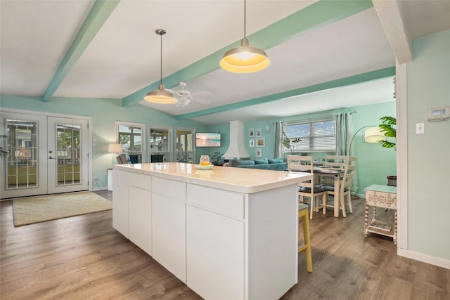 22118 Matagorda Dr, Galveston, TX 77554 - kitchen featuring pendant lighting, white cabinets, a kitchen island, and wood finished floors